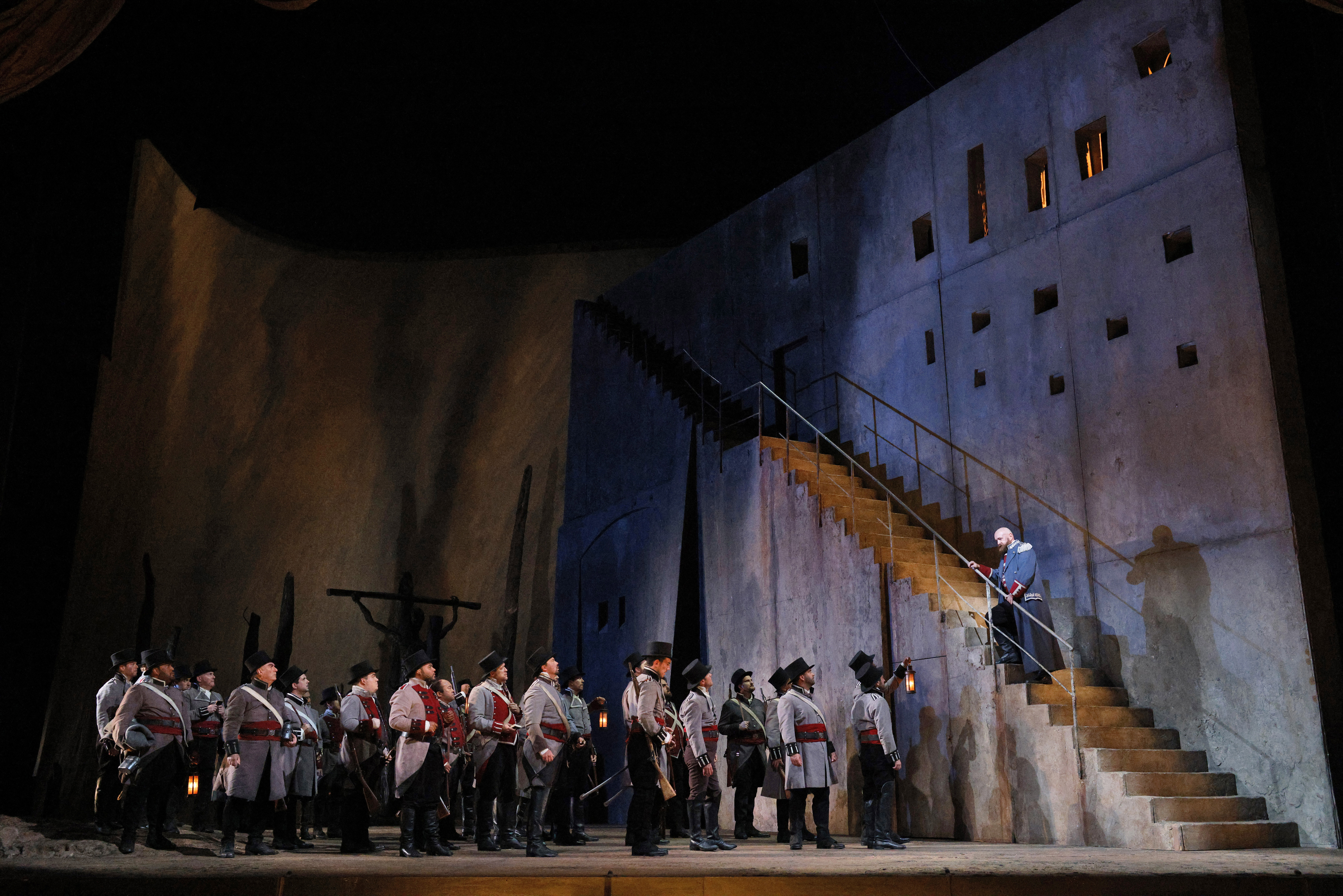 man on stage is standing midway up the stairs as he sings to soldiers