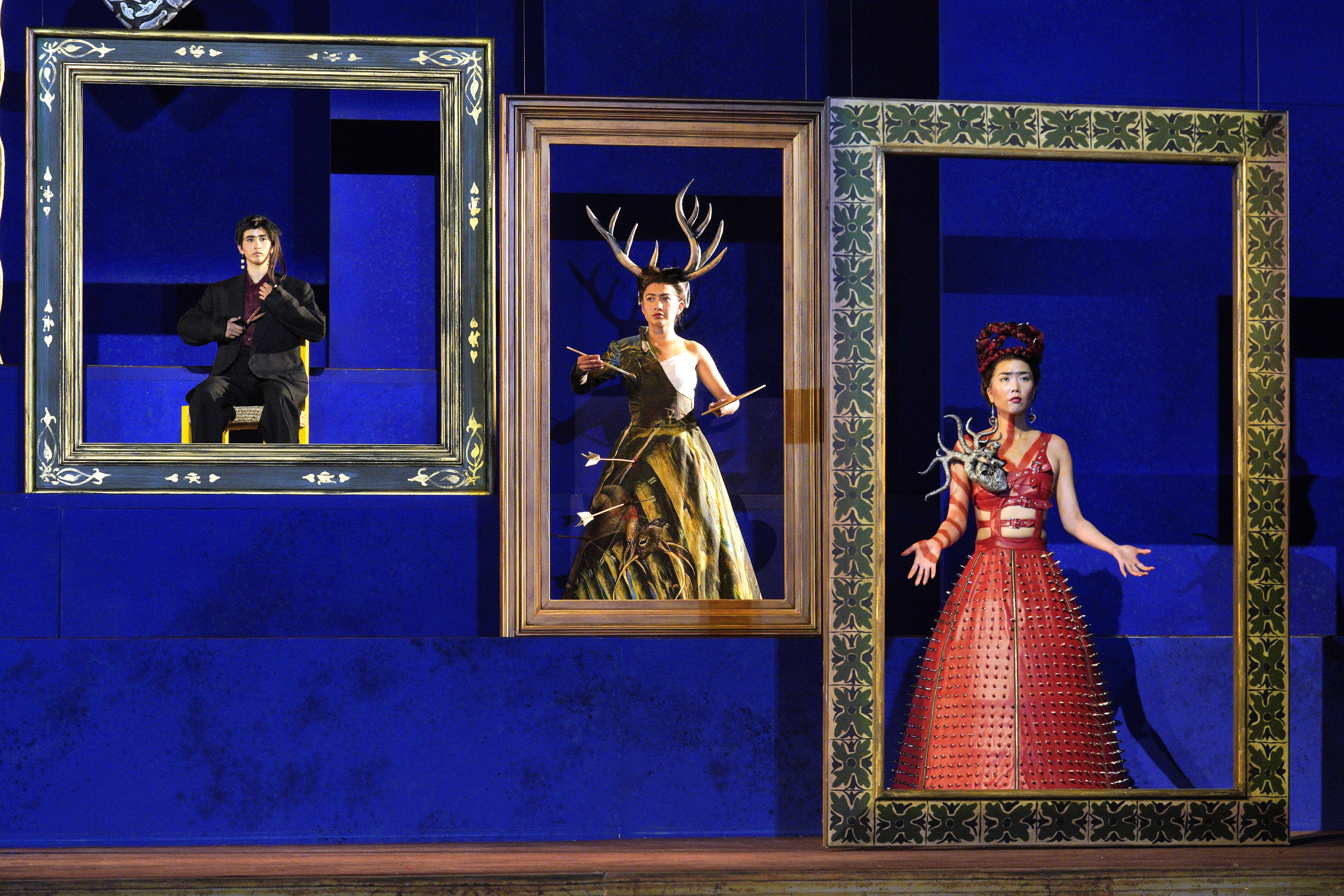 Scene from Frida of three people each standing inside a picture frame