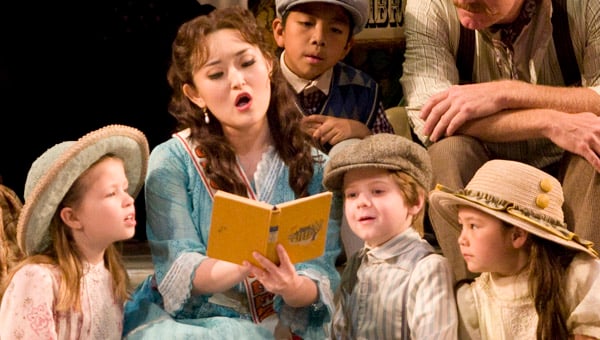 The Elixir of Love cast performing. A teacher is reading a book to children.